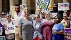 Buffalo Common Council candidates Matt Dearing, Kathryn Franco, Eve Shippens, and India Walton pose for a photo during a campaign event outside of Buffalo's City Hall, June 26, 2023. They are surrounded by supporters smiling and holding campaign signs.